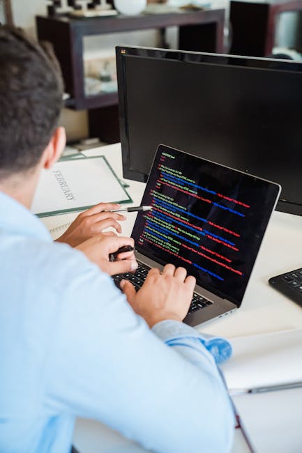 A close-up view of a modern laptop with a white keyboard, displaying a software development environment on the screen. The screen shows lines of code in a text editor alongside a large, orange calcula